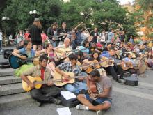 group of guitar players sitting in a park