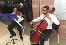 Two young men performing, one playing the violin, the other the cello
