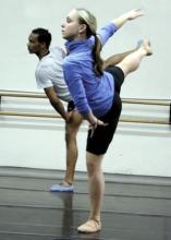 Two dancers in the studio with right right arms and legs extended out to side