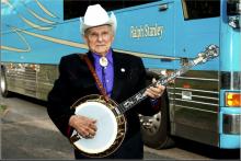 Ralph Stanley, bluegrass musician standing in front of his band's tour bus