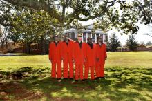 Five men wearing red suits stand outside wearing sunglasses