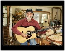 a man holding a guitar in his luthier's workshop