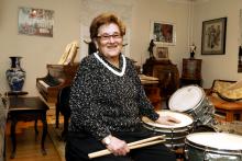 A woman sits in front of a drum set