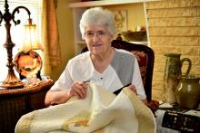 A woman sitting in a chair holds a quilt