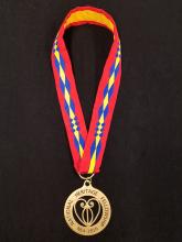 circular medal with filigree heart in cut-out center hung from red, blue and yellow ribbon in Osage traiditional patter