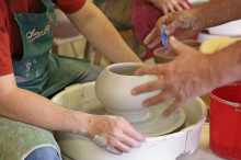 Arms and hands of people working on a pottery wheel