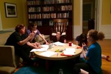 The five residents sitting around a coffee table communicating using ASL.