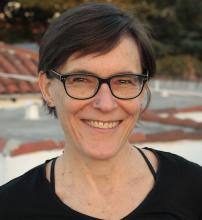 a white woman with short hair, a nose stud,  and glasses