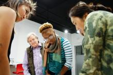 Three women and one men look down at a table