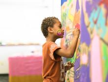 A little boy painting a mural