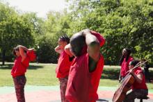Group of people in red outfits, some with musical instruments, in Central Park. 