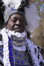 A man in an elaborate blue, white, and silver headress and suit. 