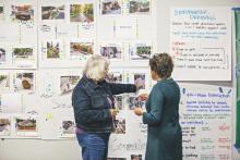 Two women standing in front of wall of pinned-up easel sheets