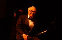 Dave Brubeck sitting at piano smiling. 