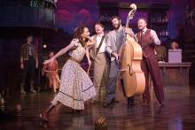 Actors and actresses with an upright bass perform onstage