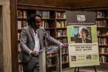 Author standing behind a podium speaking to a crowd of people. 