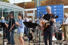 Man with white hair and mustache playing guitar with band