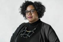 A woman with black curly hair and funky glasses
