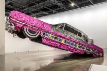 Life-size lowrider car piñata hanging in a museum