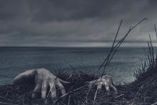 a pair of hands is the only visible part of a body that appears to be hanging from a cliff's edge