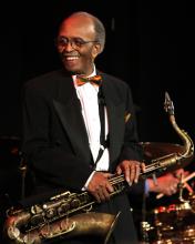 A man stands on a stage holding a saxophone