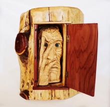 wood carving of a wrinkled face inside a log
