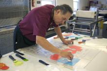 Artist Jim Denomie working in the printmaking studio at Crow's Shadow