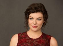 Head shot of woman with curly brown hair and sleeveless red dress