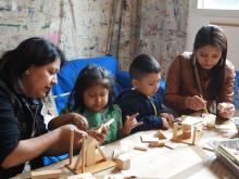 Two mothers building wooden sculptures with two children