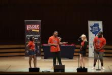 a group of four students on a stage with festival banners behind them