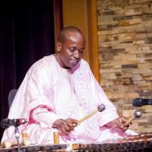 a dark-skinned man playing a balafon