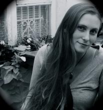 a young white woman with long dark hair sits in a back garden