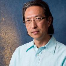 a Japanese-American man with medium length salt and pepper hair and glasses