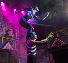 Acrobat standing atop another acrobats shoulders