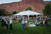 Festival attendees walking around with red rocks in the background and white tents posted up. 