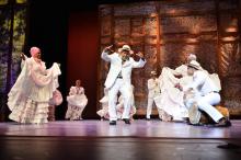 Heritage Fellow Modesto Cepeda on stage with male and female dancers in traditional white Puerto Rican costumes
