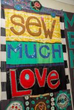 A colorful quilt that says Sew Much Love