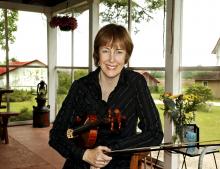 Woman in suit holding a fiddle. 