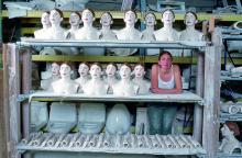 Woman standing with a bunch of ceramic renditions of her. 