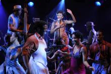 Woman singing at the mike in a nightclub with people dancing in front of her. 