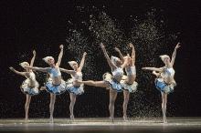 Dancers in tutus with arms in the air, dancing.