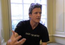 Man in black shirt gesturing with his right hand.