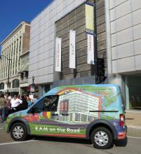 A colorful bus parked in front of a museum. 