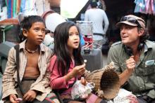 Director wearing hat with two Laotian children. 
