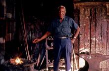 Man standing next to a fire for blacksmithing. 