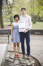 Woman and man holding a sign. 