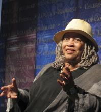 Toni Morrison wearing hat, sitting and gesturing with her hands