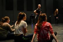 A laughing man stands in a circle of seated high school students
