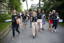 A group of young people sing as they march through a street