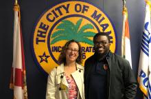 A smiling woman stands with a man in front of a police sign